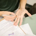 A person writing notes on the palm of his hand during what looks like an exam