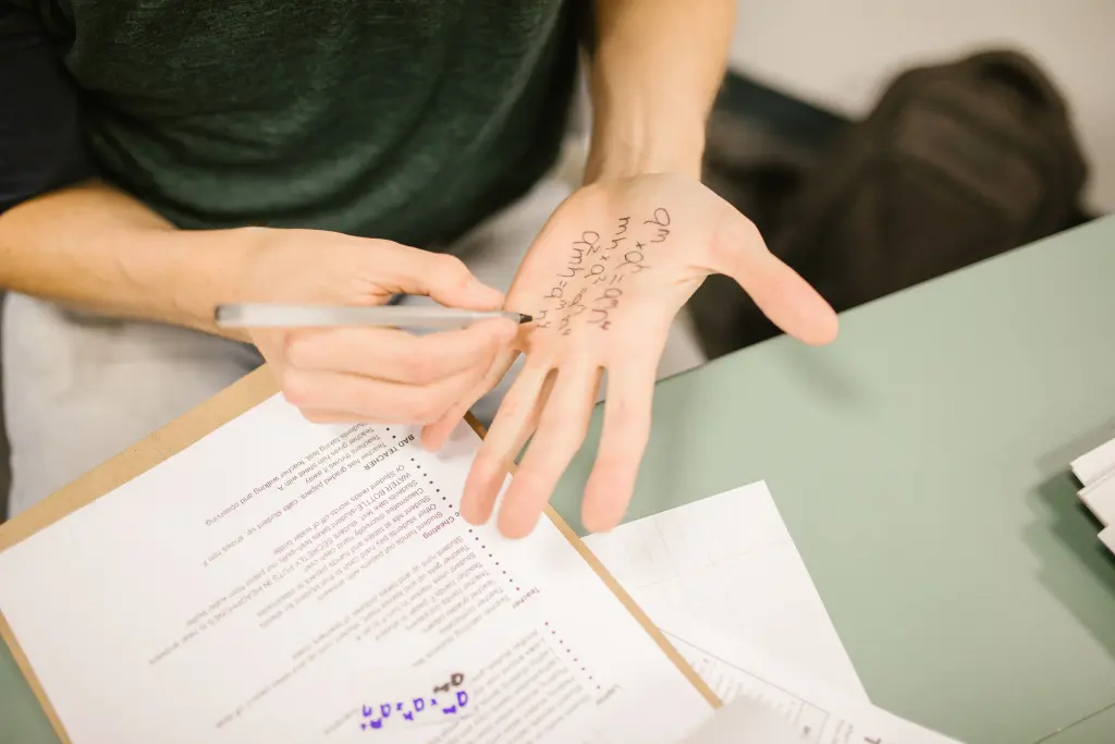 A person writing notes on the palm of his hand during what looks like an exam