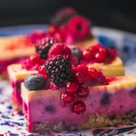 Slices of a pink fruit cake with fresh berries on top