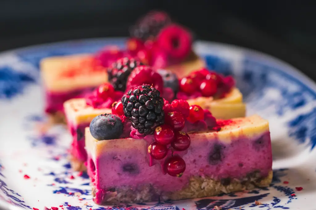 Slices of a pink fruit cake with fresh berries on top